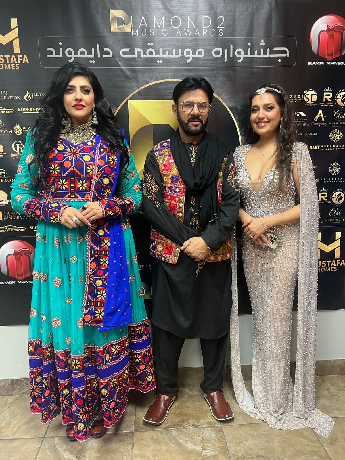 Taher Shubab in traditional Afghan dress on the red carpet at the Diamond Music Awards with two guests